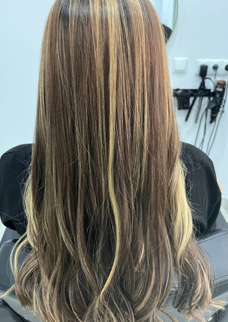 "Pelo largo con mechas rubias y efecto luminoso en salón de peluquería y estilismo."